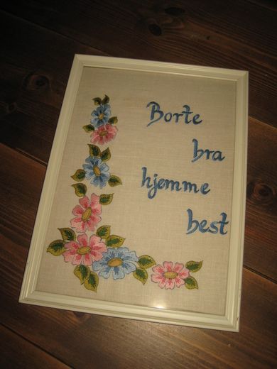 Meget pent, brodert bilde i glass og ramme, ca 24*33 cm stort. Tekst: Borte bra hjemme best. 