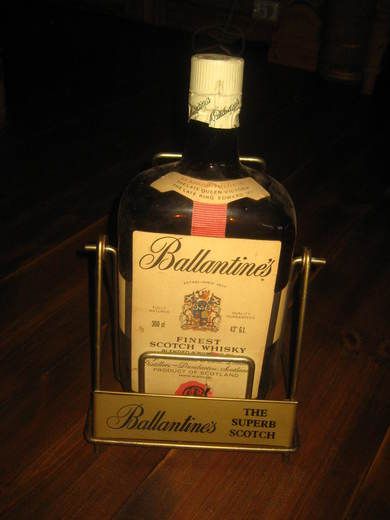 Meget stor flaske i tøfft stativ, BALLANTINES FINEST SCOTCH WHISKY. Kan det vere reklame på et vinmonopol utsalg, en skikkeleg pen reklamesak. Ca 39 cm høg i messing stativ. 